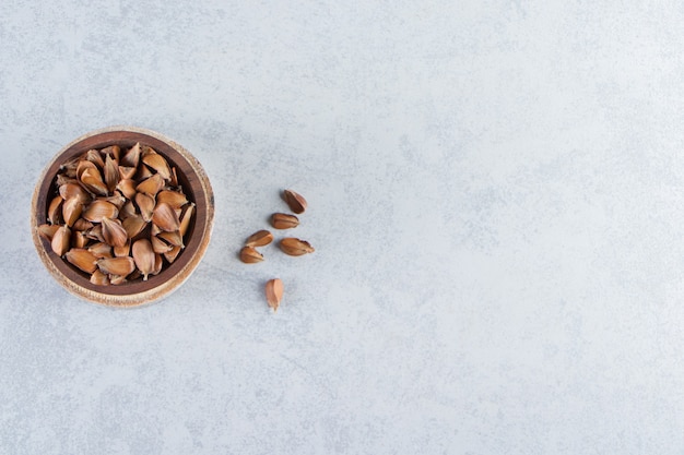 Wooden bowl of many crunchy seeds on stone background.