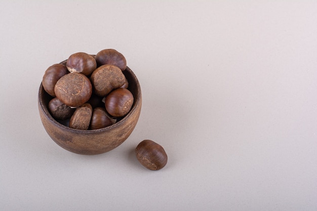 Wooden bowl of organic dry chestnuts on white background. High quality photo