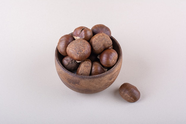 Wooden bowl of organic dry chestnuts on white background. High quality photo