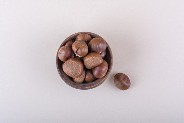 Wooden bowl of organic dry chestnuts on white background. High quality photo