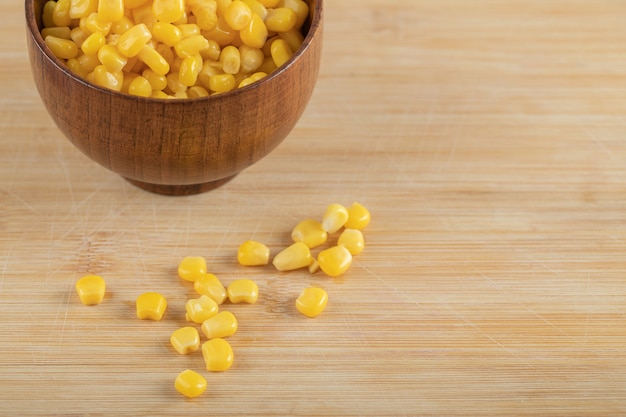 A wooden bowl of popcorn seeds on wooden table.