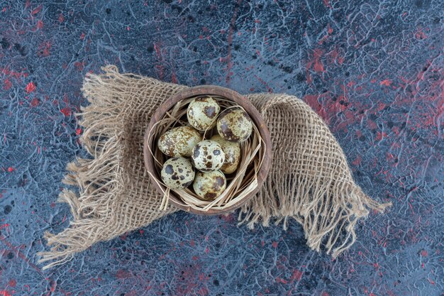 A wooden bowl of quail eggs on a sackcloth .