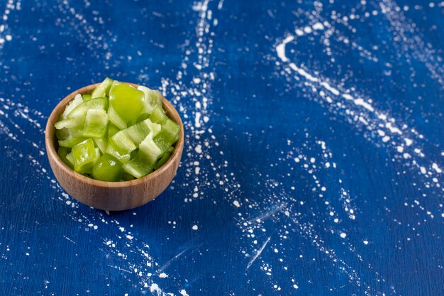 Free photo wooden bowl of sliced green bell peppers on marble surface