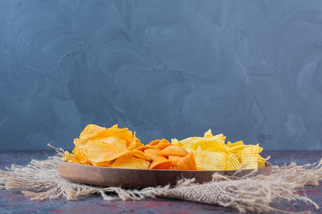 Wooden bowl of snacks for beer on a dark background.