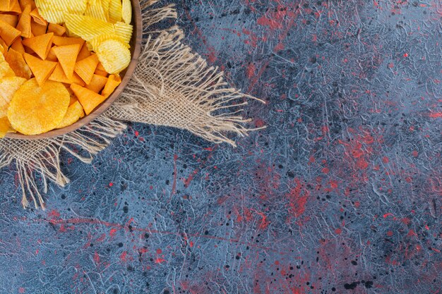 Wooden bowl of snacks for beer on a dark surface