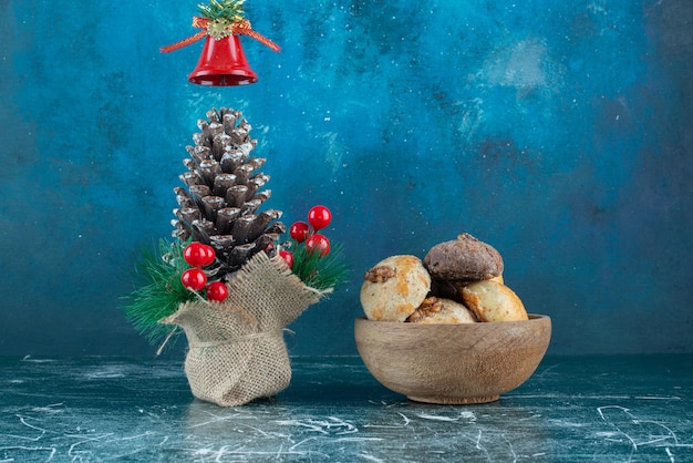 A wooden bowl sweet cookies with Christmas pinecone.