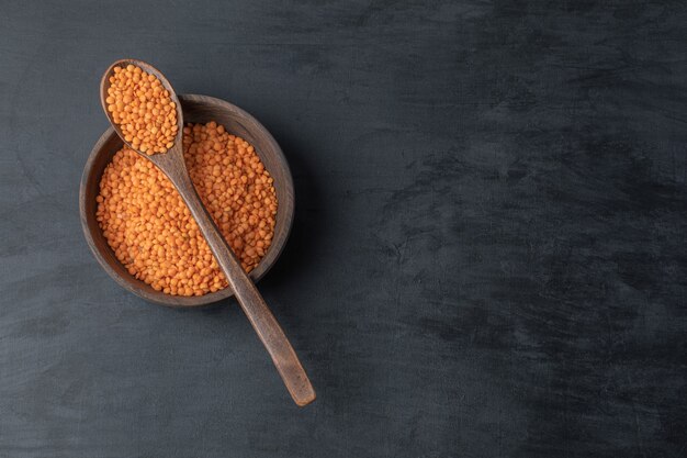 A wooden bowl of uncooked lentil beans .