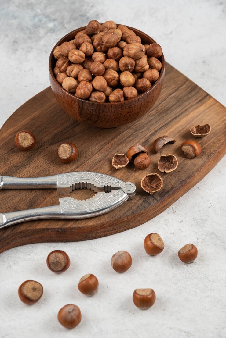 Free Photo wooden bowl of unpeeled organic hazelnut kernels on cutting board. 