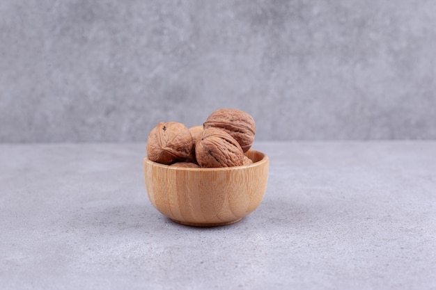 Деревянная миска грецких орехов на мраморном фоне. Фото высокого качества