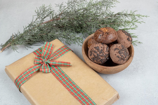 A wooden bowl with chocolate cookies with Christmas present.