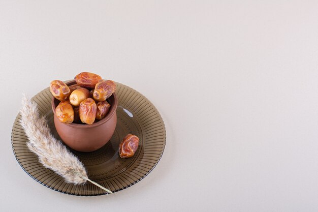 Деревянная миска с сушеными вкусными финиками на белом фоне. Фото высокого качества