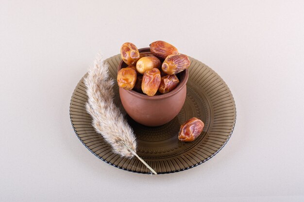 Wooden bowl with dried tasty dates on white background. High quality photo