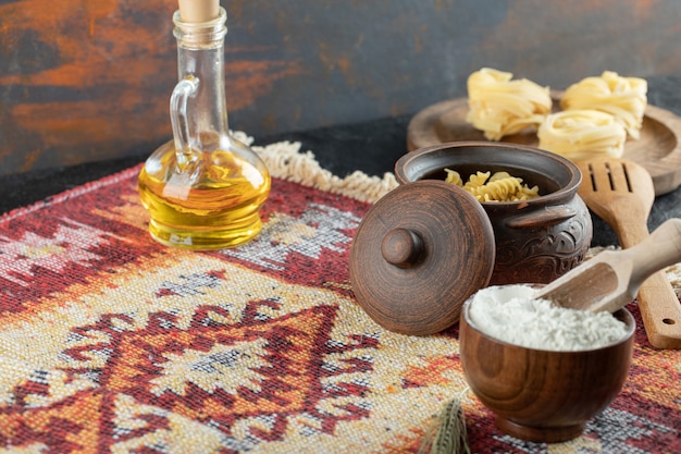 A wooden bowl with flour and with pot of raw pasta 