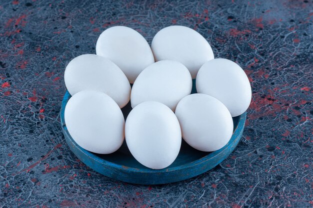 A wooden bowl with fresh raw chicken eggs 