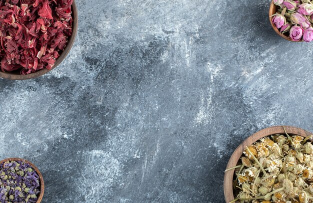 Wooden bowls of dried flowers on marble table. 