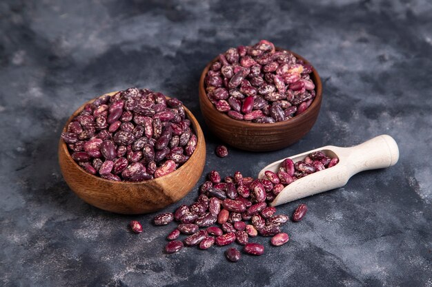 Wooden bowls full of raw grains of dried beans on black