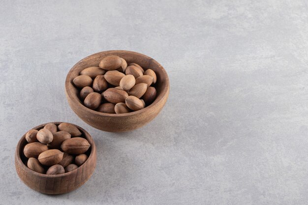 Wooden bowls of organic shelled walnuts on stone background. 