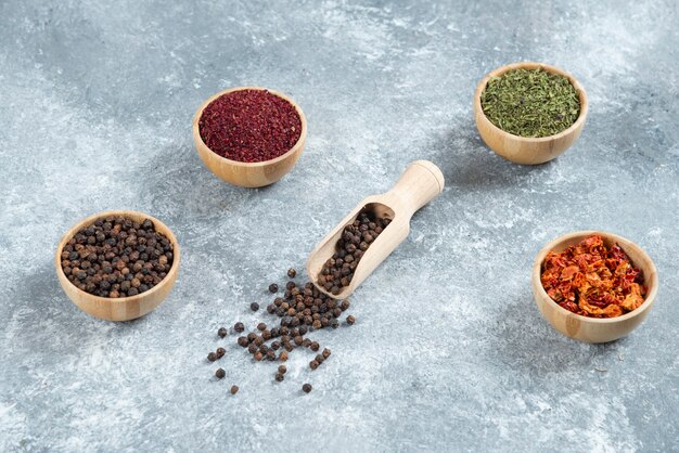 Wooden bowls of various spices on marble background.