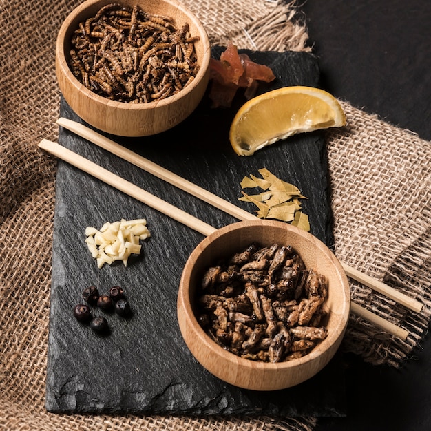 Free photo wooden bowls with roasted silkworms