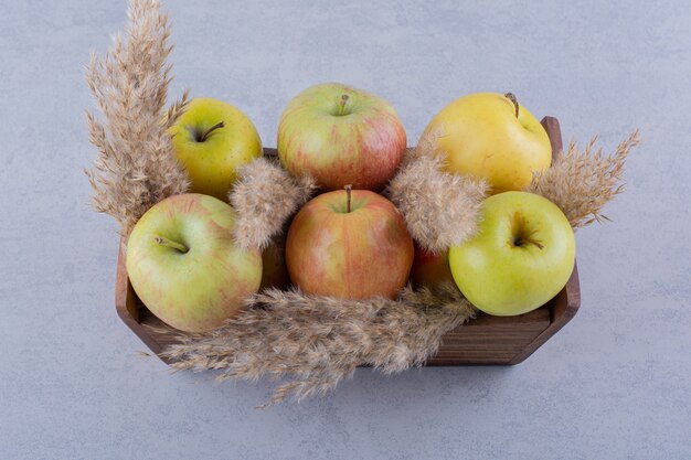 Wooden box of fresh green apples on stone.