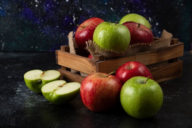 Wooden box of fresh organic apples on black surface. .