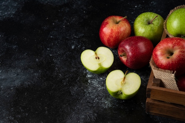 Wooden box of fresh organic apples on black surface. .