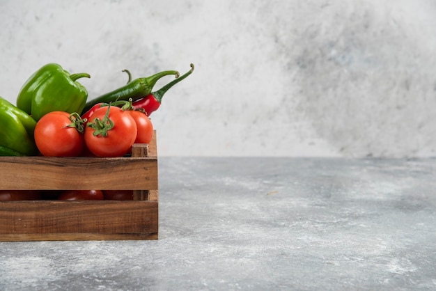 Wooden box full of fresh vegetables on marble.