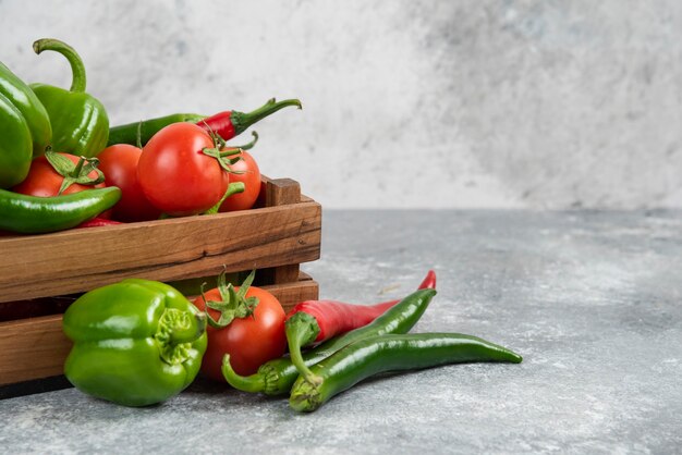 Wooden box full of fresh vegetables on marble.