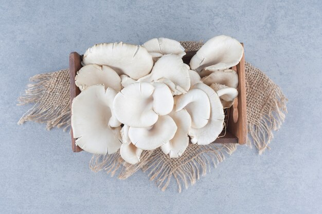 Wooden box full of oyster mushroom on sack. 