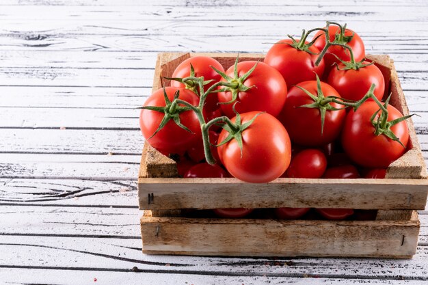 wooden box full of red tomatoes on white wood