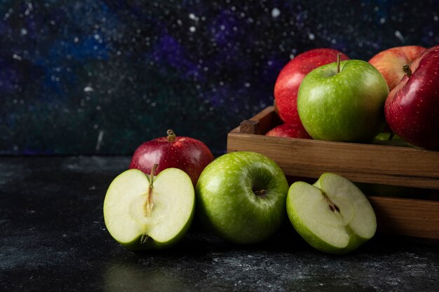 Wooden box of ripe organic apples on black surface. .