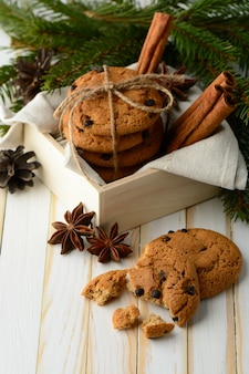계피 스틱과 침엽수 향기로운 가지로 구성된 달콤한 초콜릿 칩 쿠키가 들어있는 나무 상자. 프리미엄 사진