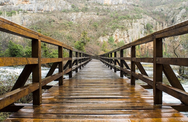 Wooden bridge surrounded by rocks covered in greenery in Krka National Park in Croatia