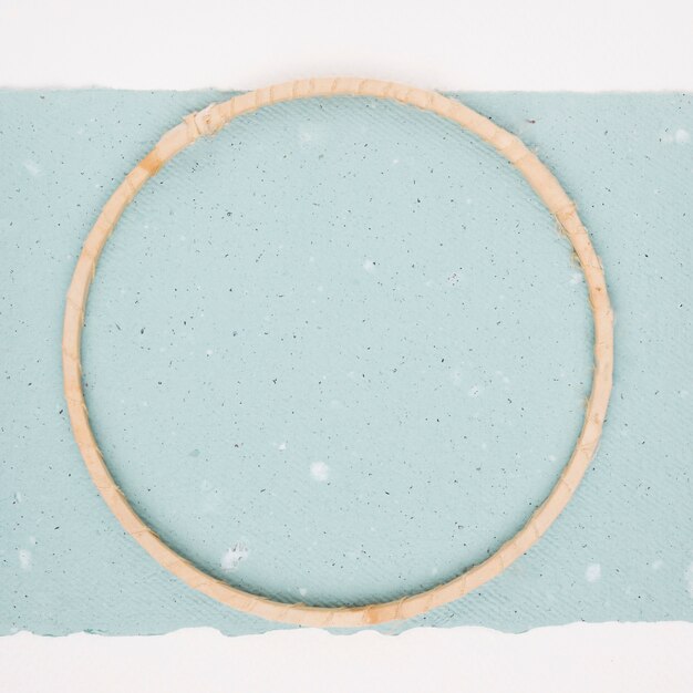 Wooden circular frame on textured blue paper