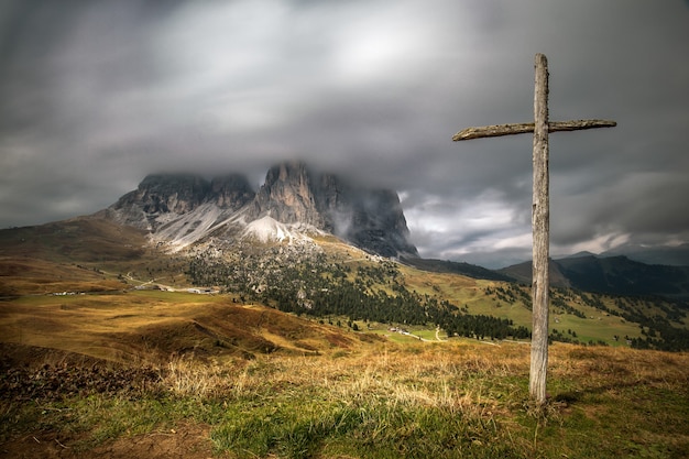 Foto gratuita croce di legno sulla collina ricoperta di verde con le dolomiti in alto adige