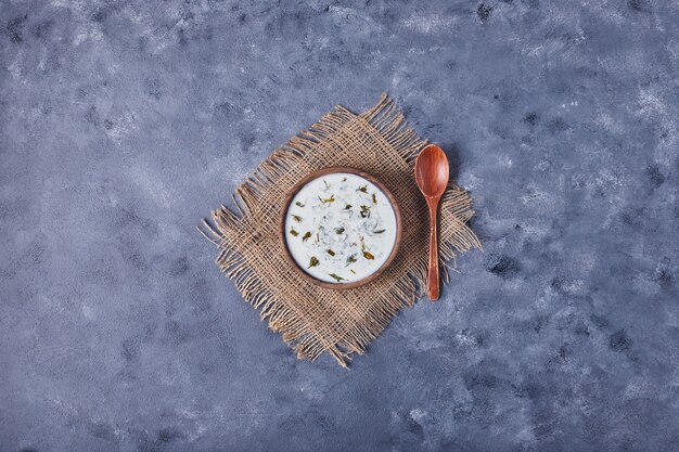 A wooden cup of yogurt soup with herbs.