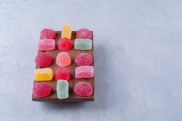 Free photo a wooden cutting board full of colorful sugary jelly candies.