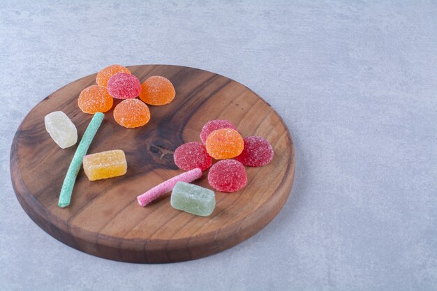 A wooden cutting board full of colorful sugary jelly candies