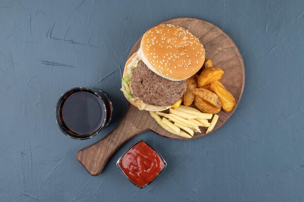 A wooden cutting board full of fried potatoes and hamburger.