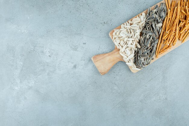 A wooden cutting board full of sunflower seeds and breadsticks. High quality photo