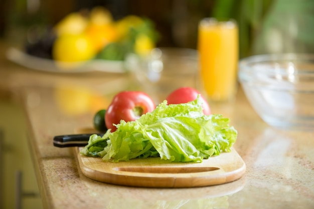 Wooden cutting board on the table with fresh vegetables on