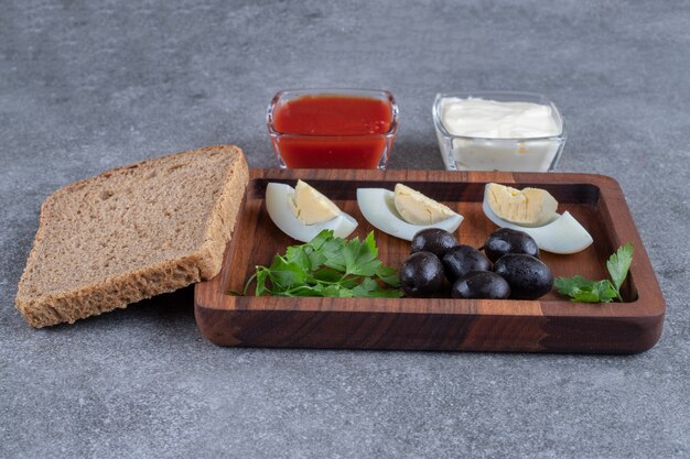 A wooden cutting board with boiled egg and slices of bread. High quality photo