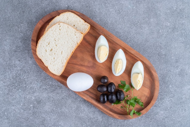 A wooden cutting board with boiled egg and slices of bread. High quality photo