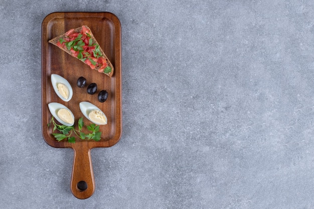 A wooden cutting board with boiled egg and toast . High quality photo