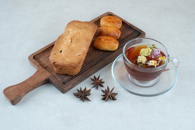 A wooden cutting board with cake and herbal tea.