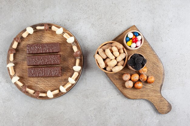 A wooden cutting board with nuts and blackberry .