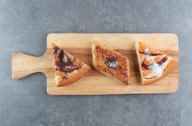 A wooden cutting board with pieces of cake 