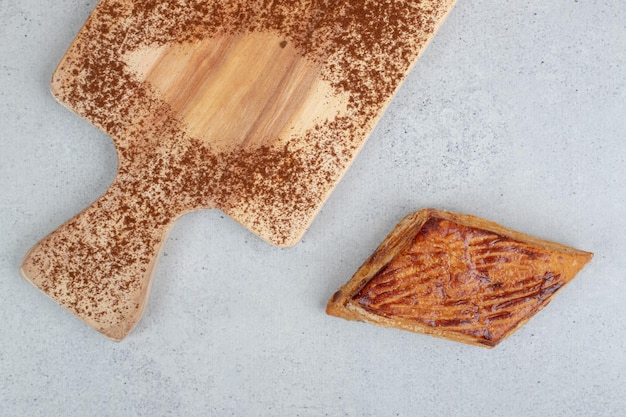A wooden cutting board with powdered cacao and cookie.