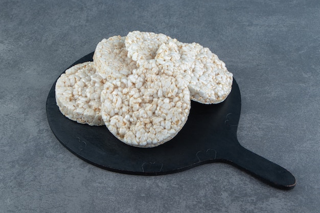 A wooden cutting board with puffed rice bread.