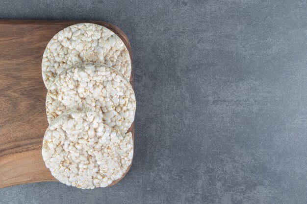 A wooden cutting board with puffed rice bread.